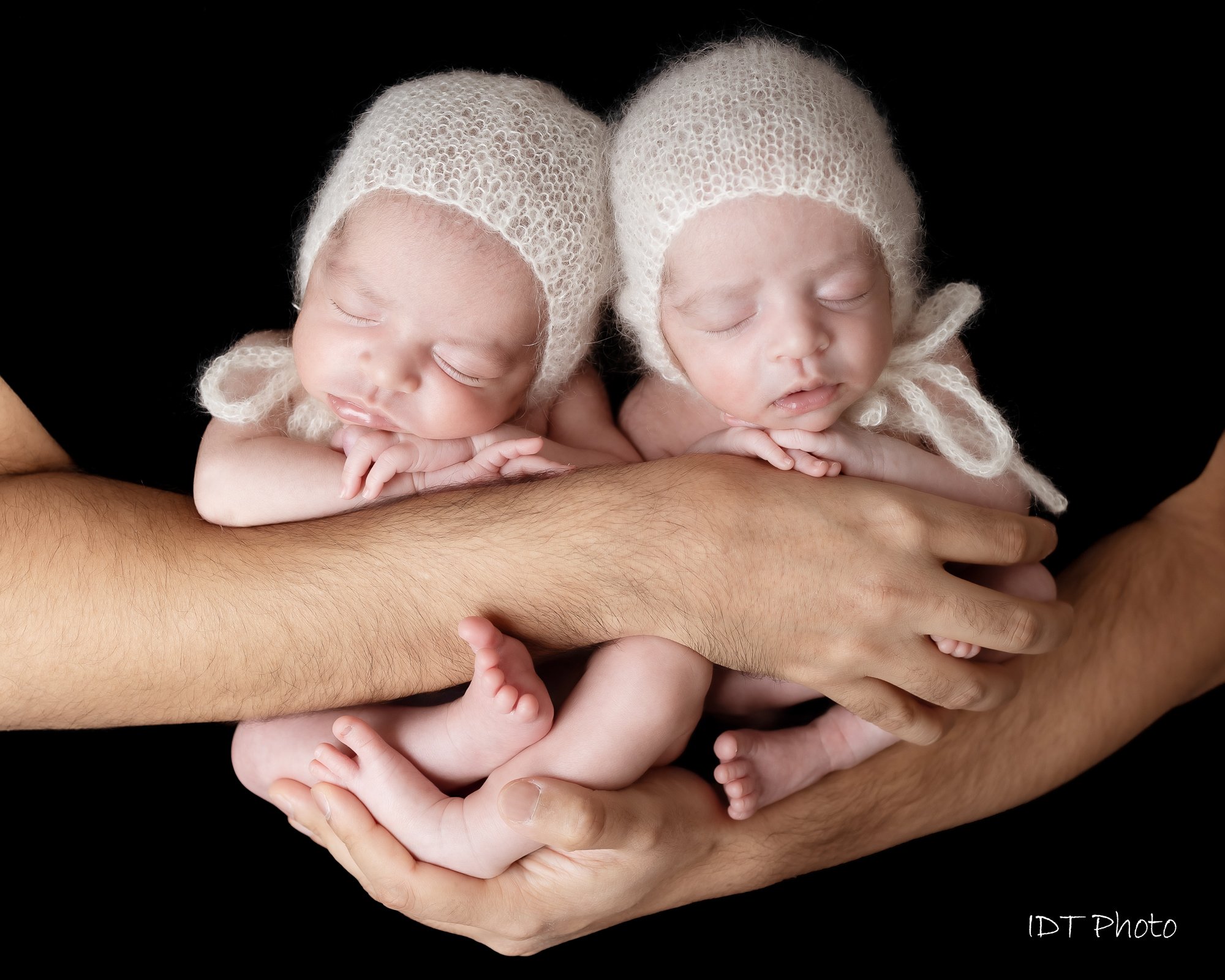 Twin newborns in white mohair bonnets cradled in father's arms — IDTPhoto Aurora IL newborn photographer