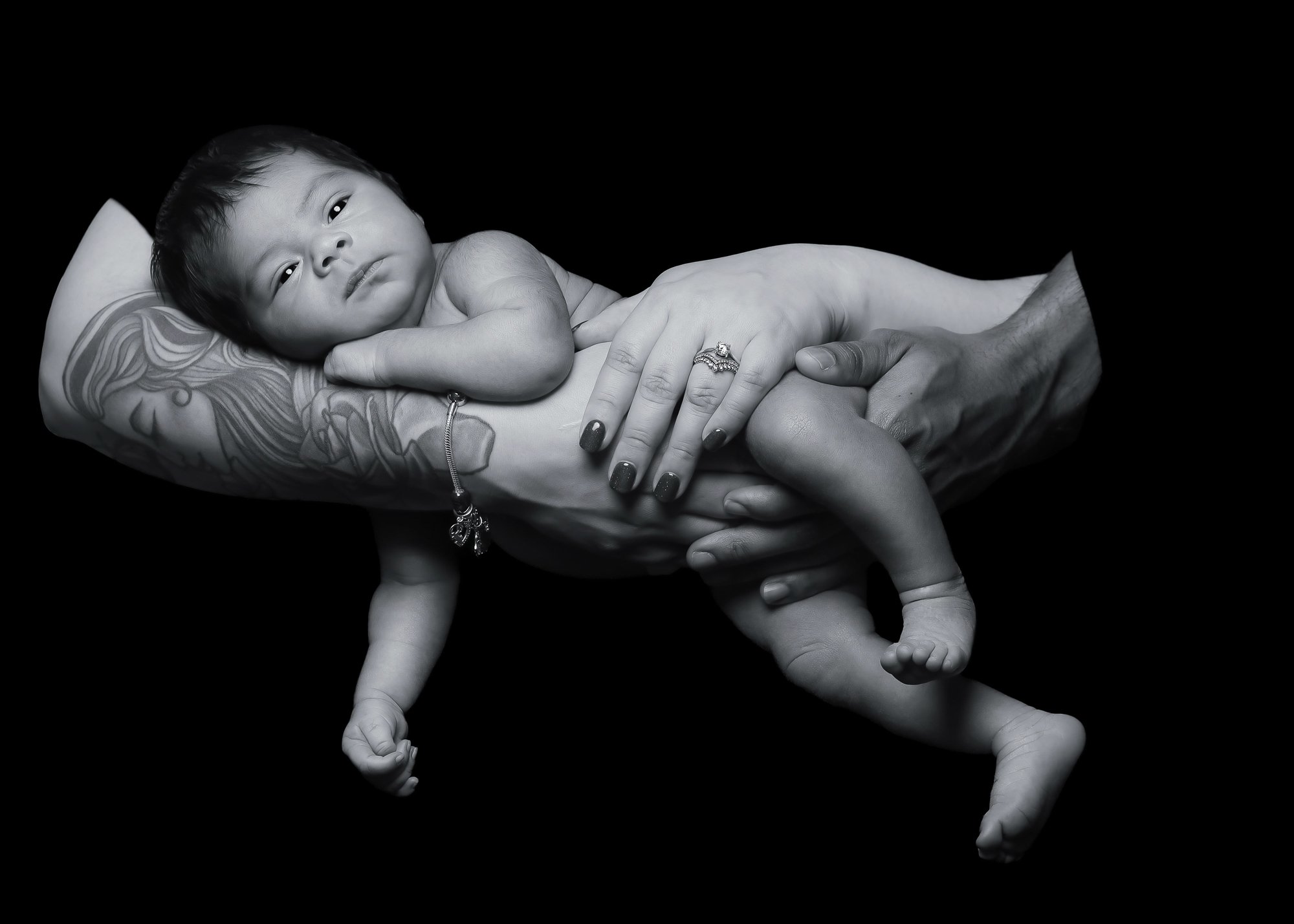 Black and white newborn portrait cradled in parents' hands — IDTPhoto Chicagoland newborn photography