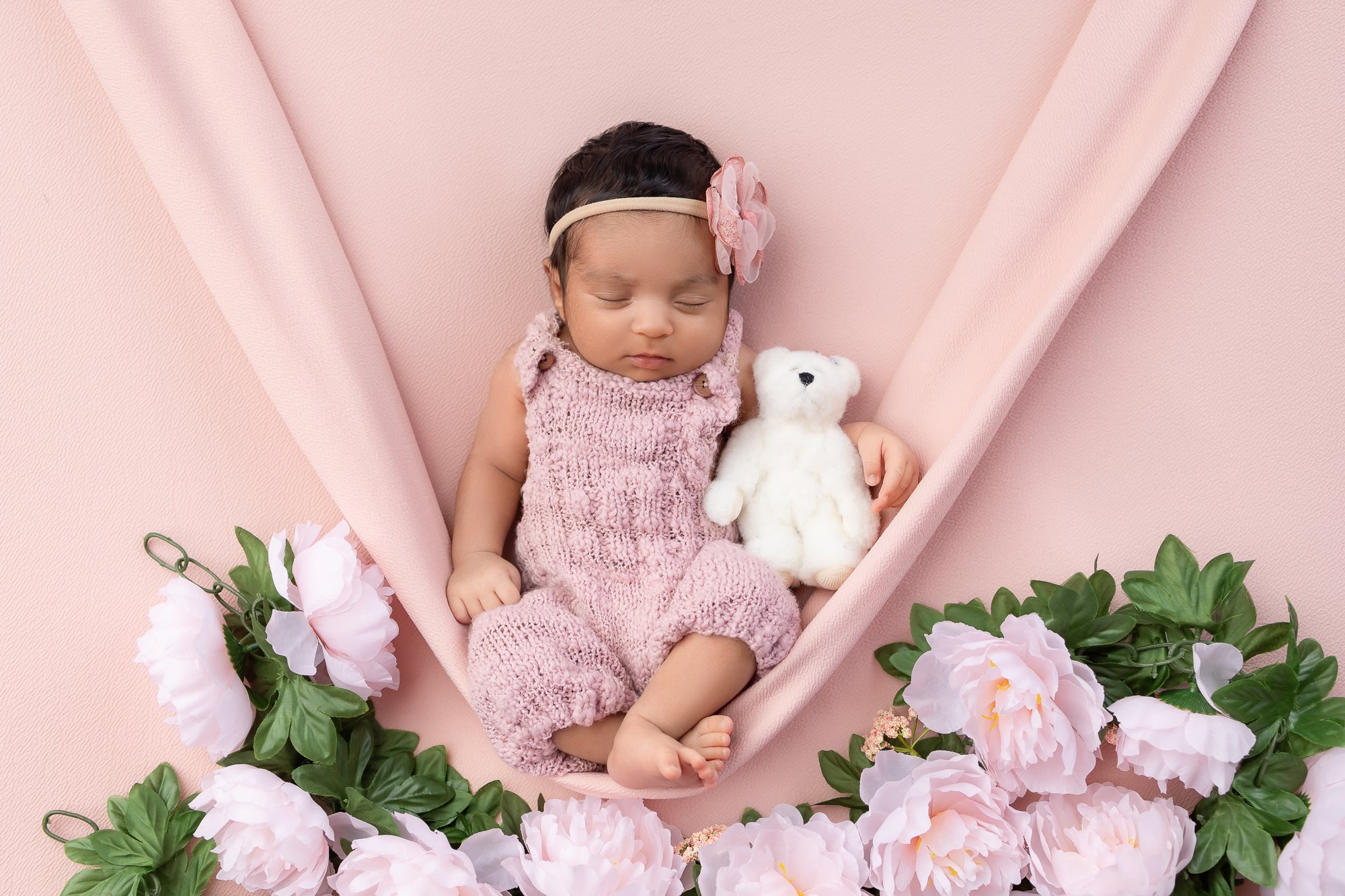 Newborn in pink hammock surrounded by peonies with teddy bear — IDTPhoto Aurora IL