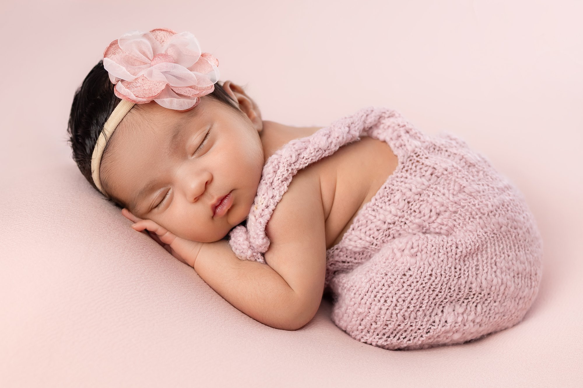 Newborn girl in pink knit romper with flower headband — IDTPhoto Aurora IL newborn photographer