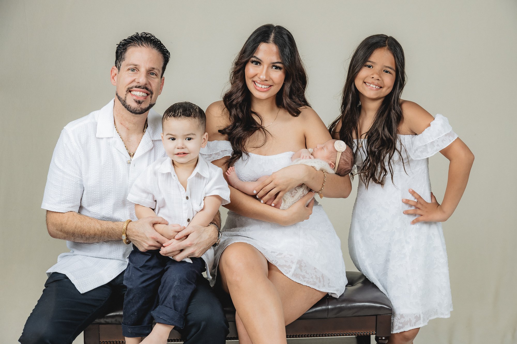 Family of five in white — parents with toddler, older daughter, and newborn girl in studio — IDTPhoto Aurora IL newborn photographer