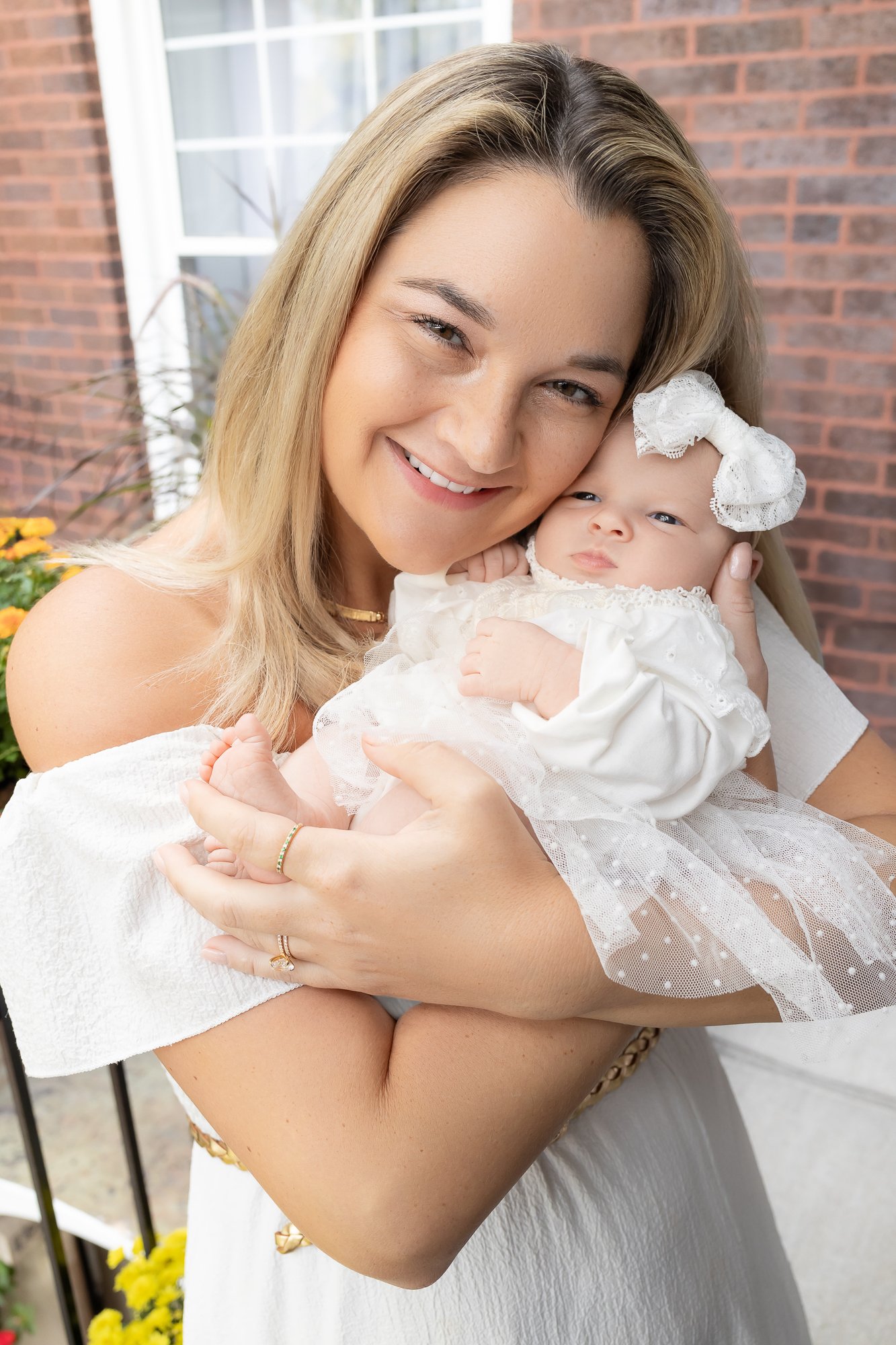Mother cheek to cheek with newborn girl in white lace bow outdoors — IDTPhoto Aurora IL newborn photographer