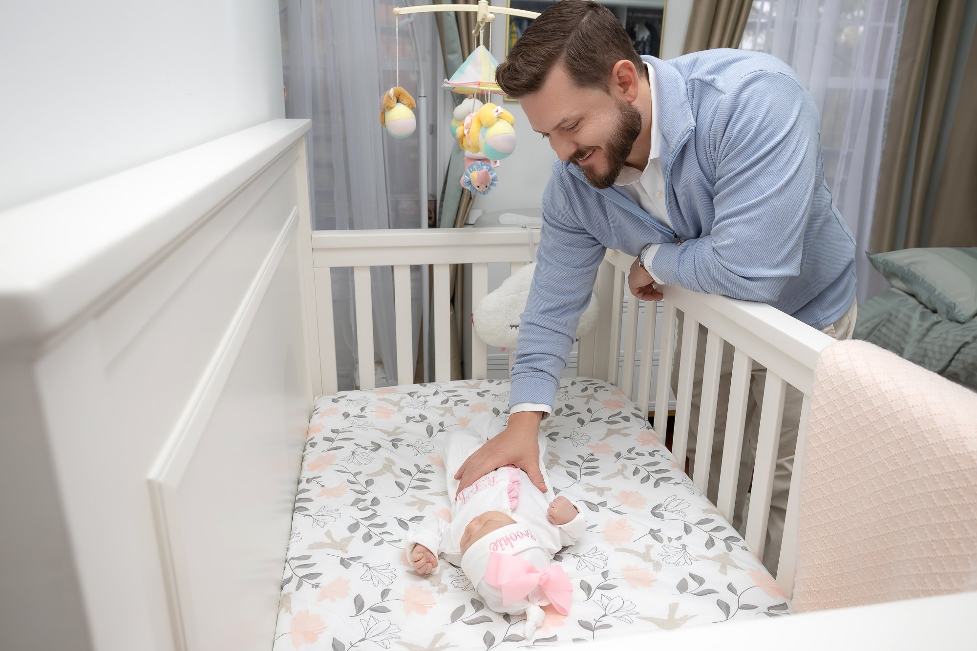 Father leaning over crib smiling at sleeping newborn in decorated nursery — IDTPhoto Aurora IL lifestyle newborn photographer