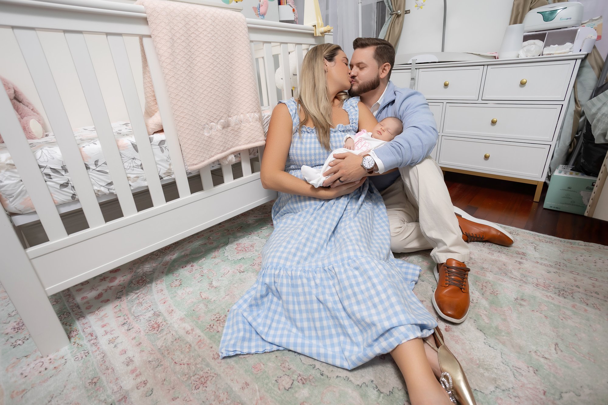 Parents sharing a kiss in the nursery while holding their newborn — IDTPhoto Chicagoland lifestyle newborn photography