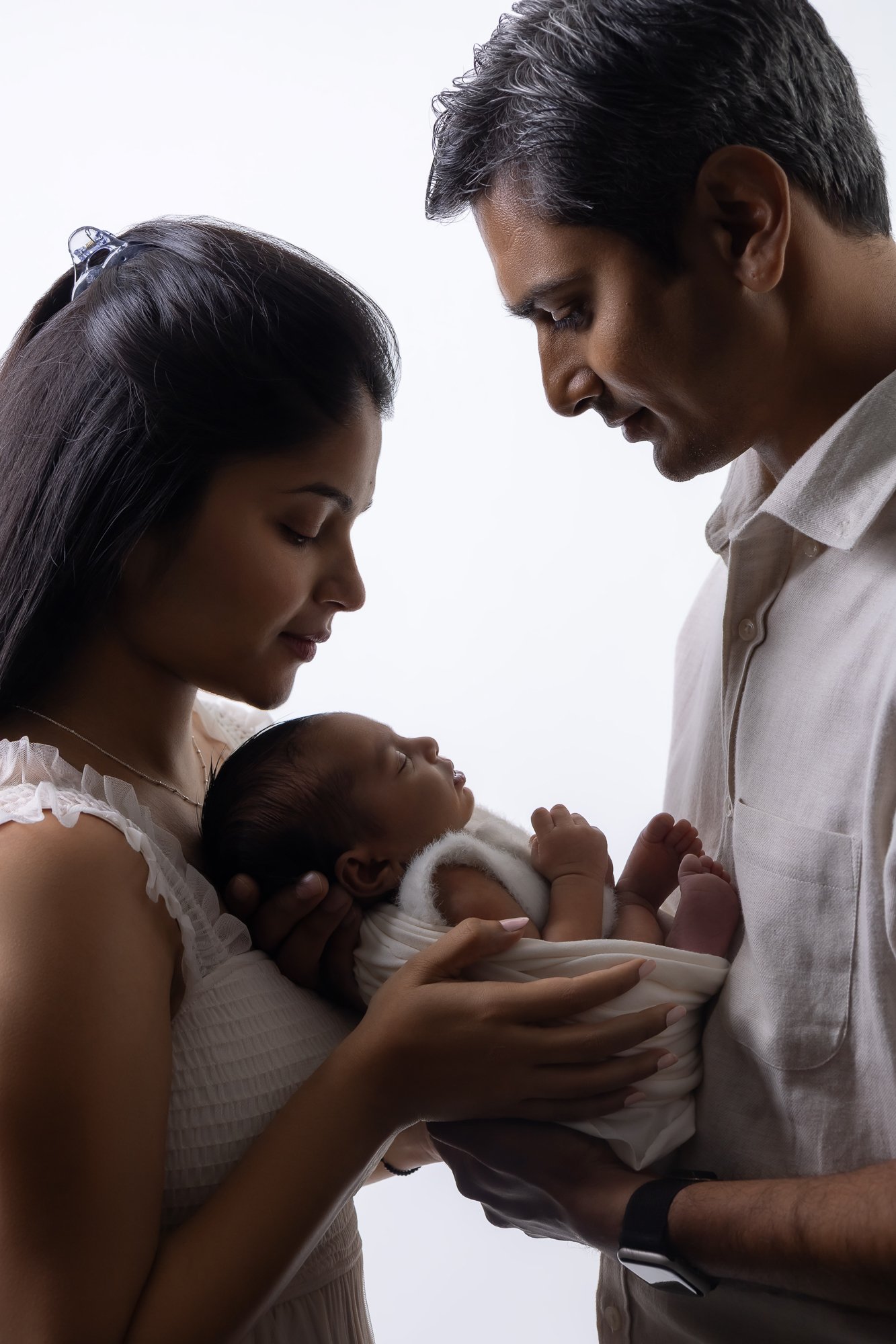 Parents gazing at newborn in backlit studio portrait — IDTPhoto Chicagoland newborn photography
