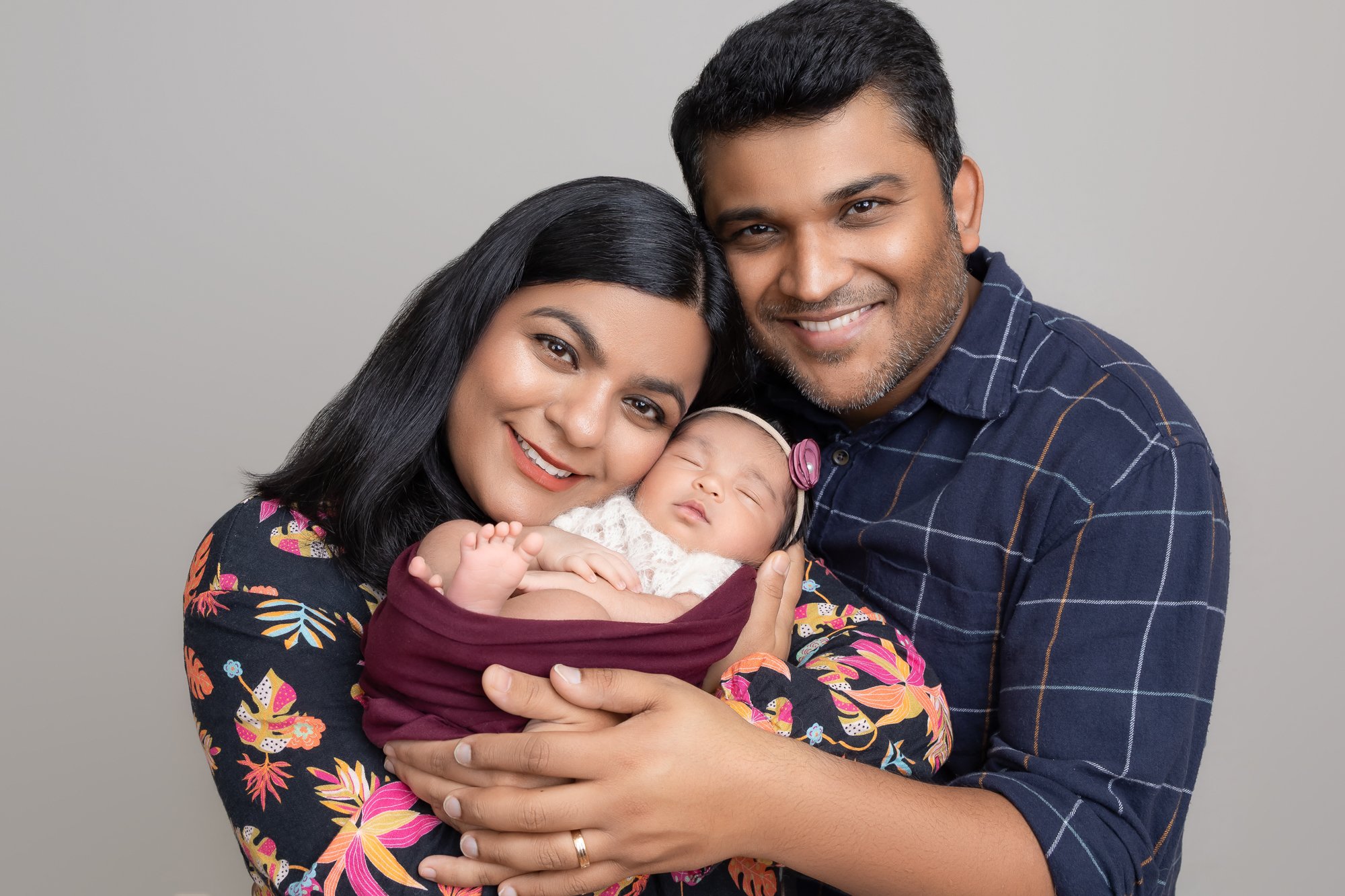 New parents smiling at camera holding sleeping newborn — IDTPhoto Aurora IL newborn photographer