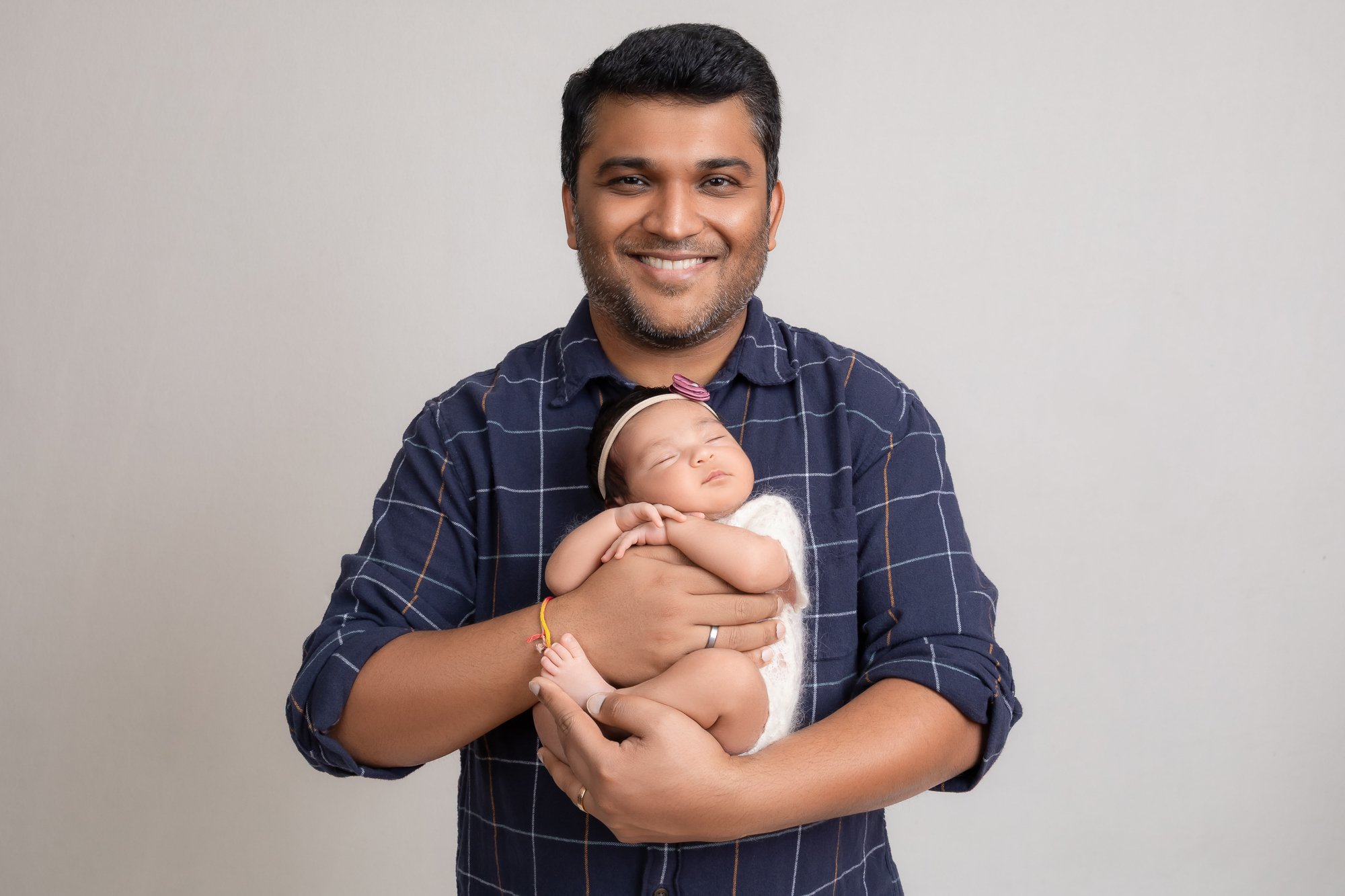 Father holding sleeping newborn girl and smiling at camera — IDTPhoto Chicagoland newborn studio